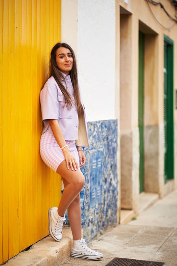 Portrait of teenage girl standing against building