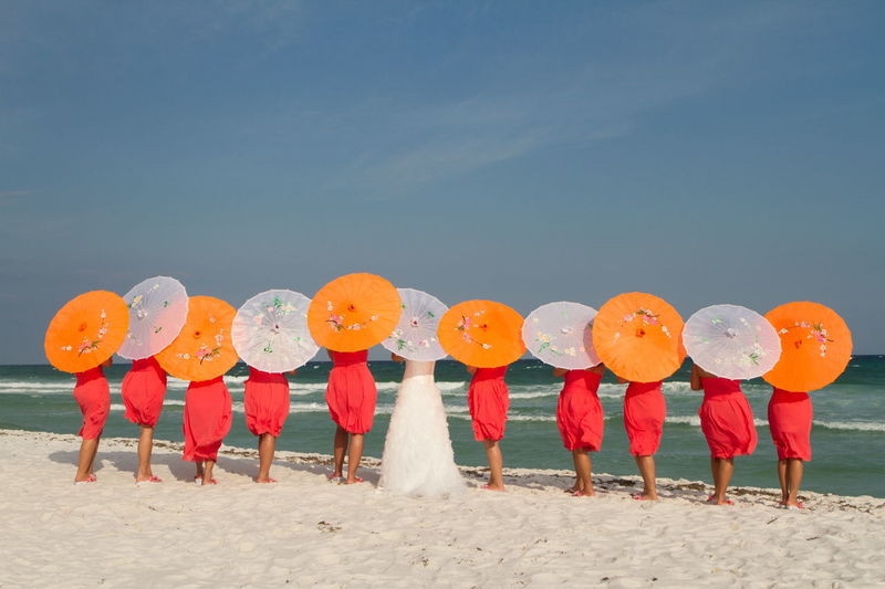 Rear view of bride with her friends standing on beach