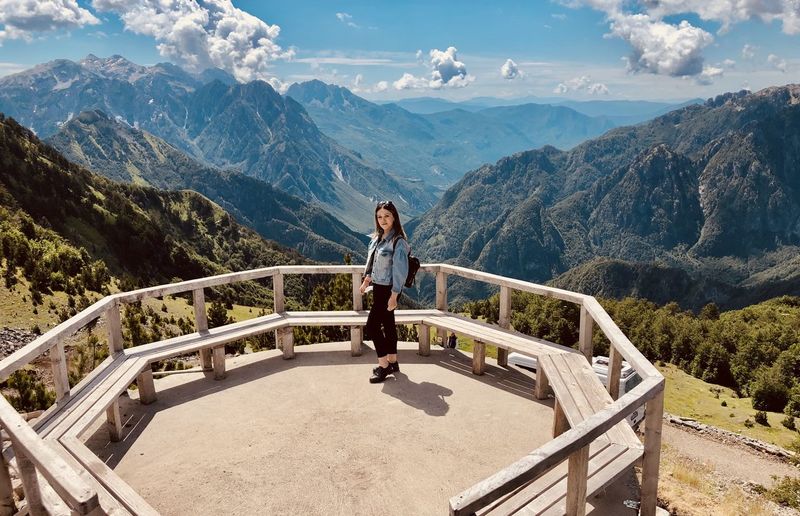 Woman standing on railing against mountains
