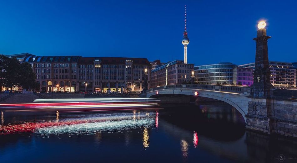 Light trail on river by fernsehturm against clear sky at dusk