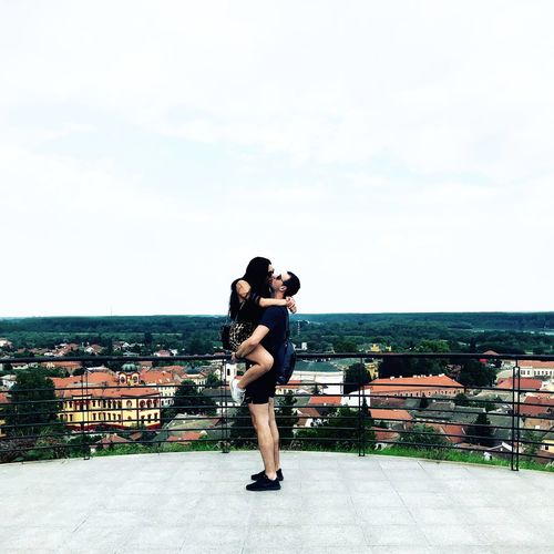 Young couple romancing on building terrace against clear sky