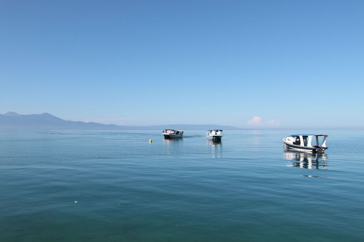 Scenic view of empty motorboats and sulawesi sea against clear sky