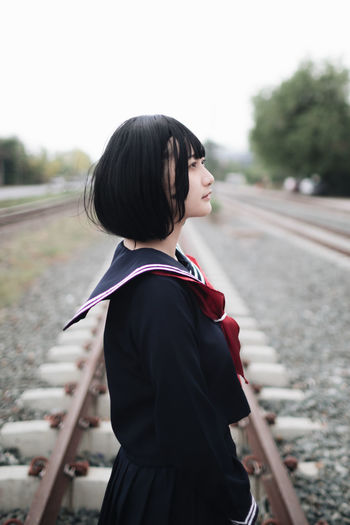 Side view of woman standing on railroad track