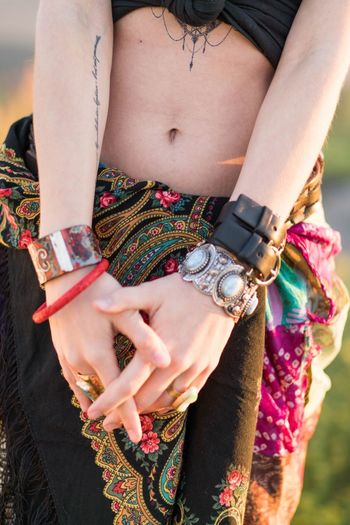 Midsection of woman in traditional cloths and bracelets in her hands during music festival