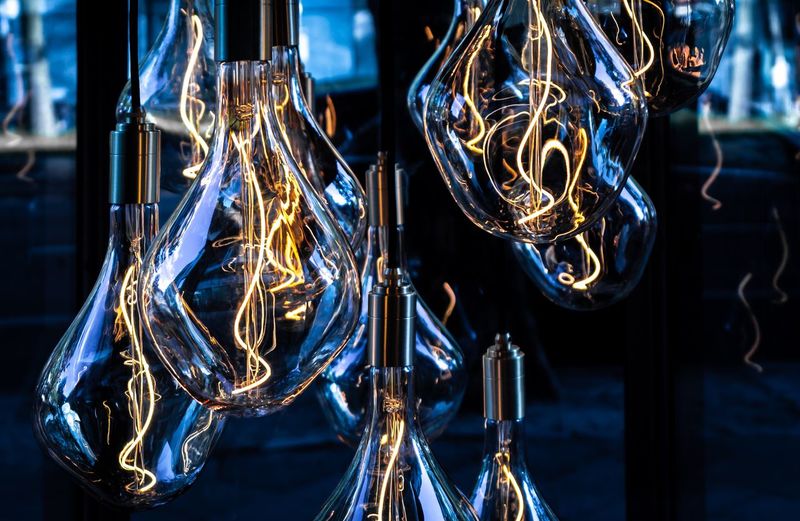 Close-up of illuminated light bulbs hanging in darkroom