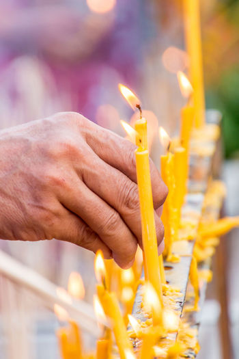Close-up of hand by lit candles in temple