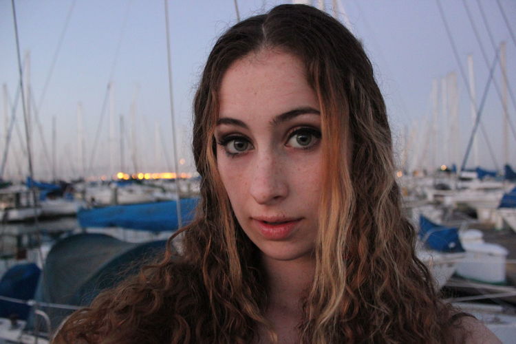 Portrait of young woman standing at harbor during sunset