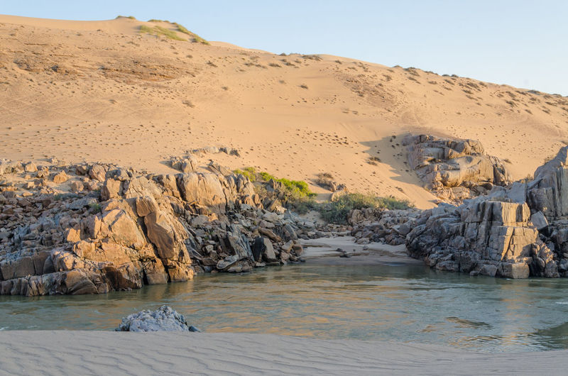 Scenic view of kunene river against dunes of namib desert and clear sky, angola, africa