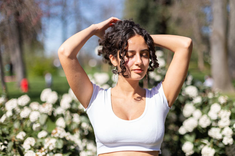 Portrait of young woman standing against trees