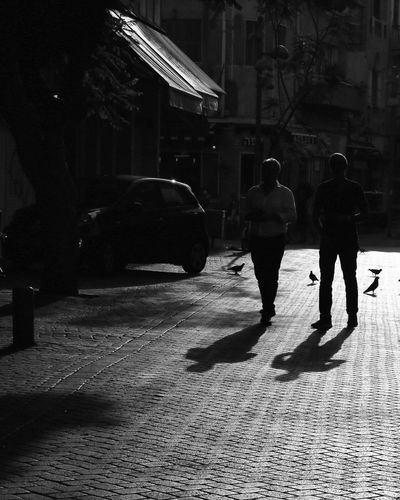 Rear view of people walking on street in city