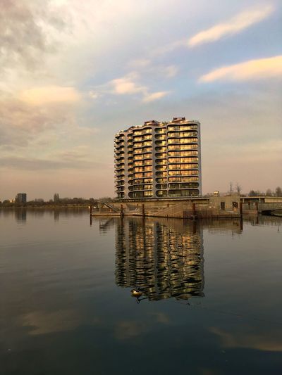 Reflection of building in lake against sky during sunset