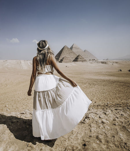 Rear view of woman standing at desert against sky