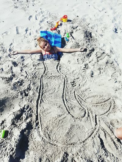 High angle portrait of smiling girl buried in sand