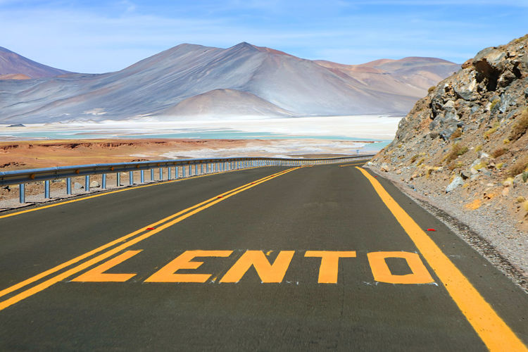 Desert road with the word lento means slow in spanish along salar de talar salt lakes, chile