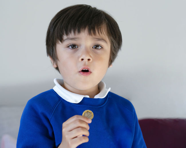 School kid showing one pound coin on his hand,child boy wearing school uniform holding money coin,