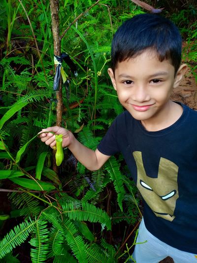 High angle view of boy holding plant leaf outdoors