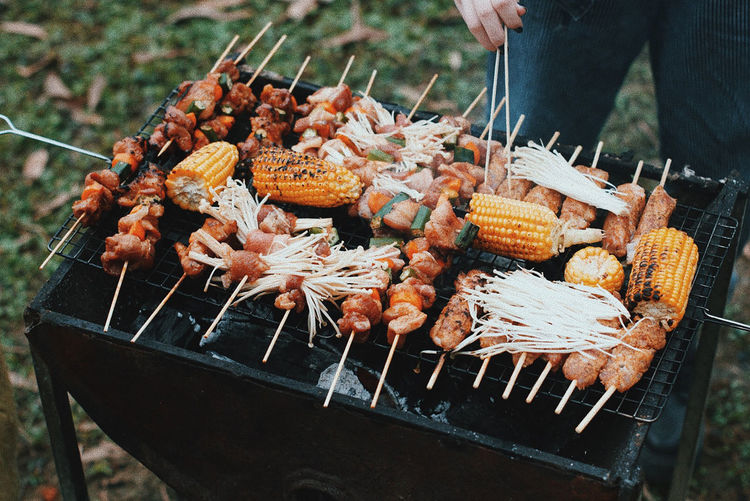 Midsection of person roasting food on barbecue grill