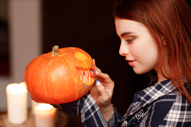 Close-up of young woman holding jack o lantern