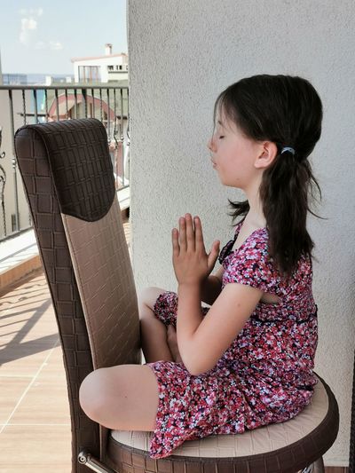 Side view of a girl sitting on chair