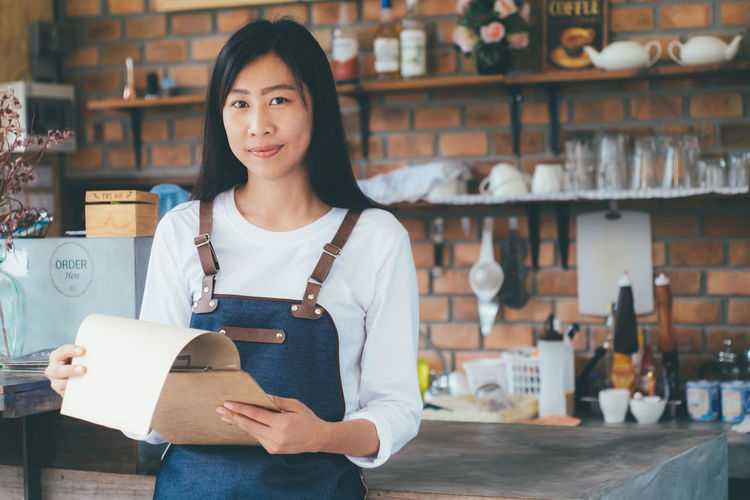 Portrait of owner with clipboard standing in store