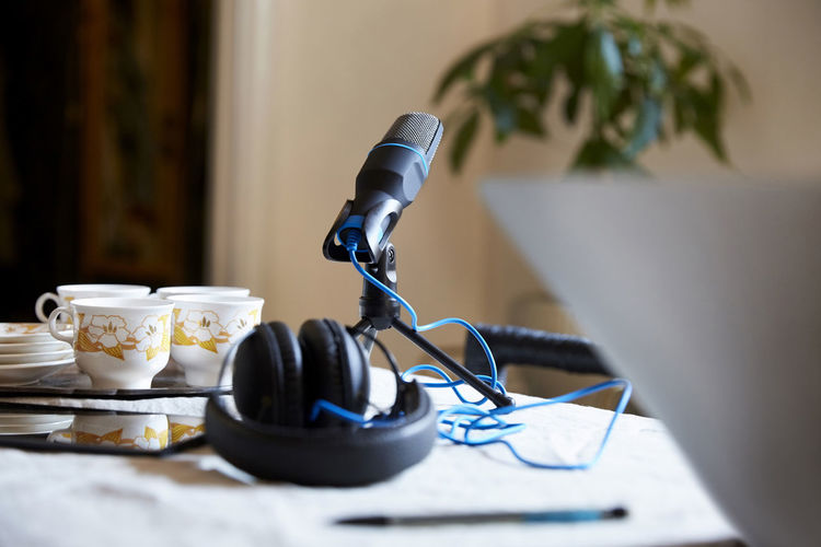 Close-up of microphone and headphones with crockery on table at home