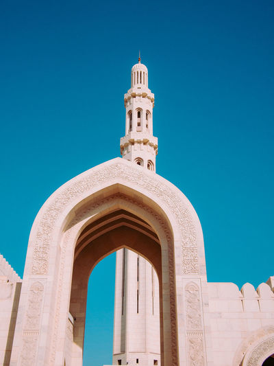 Low angle view of mosque entrance against clear blue sky