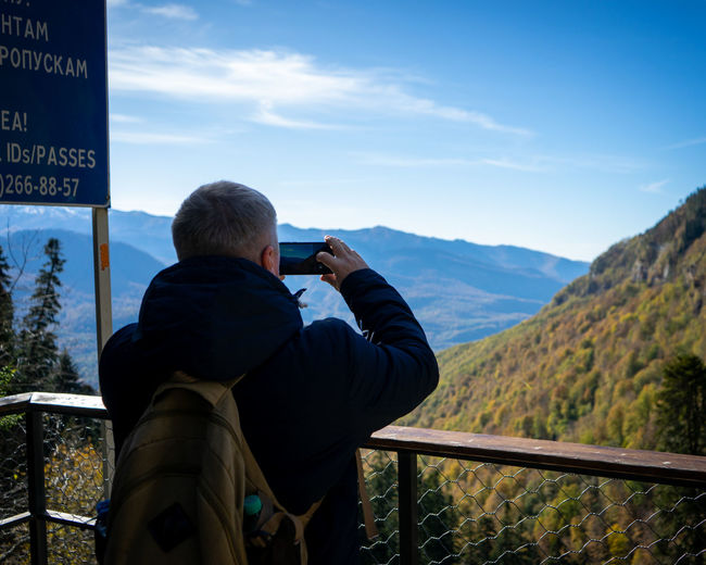 Rear view of man photographing on mountain