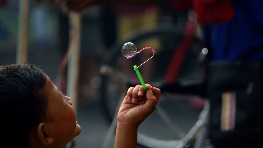 Close-up of little boy playing with bubble wand