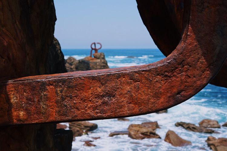 Close-up of rusty metal by sea against clear sky