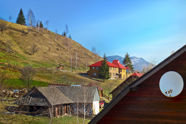Houses amidst trees and buildings against blue sky