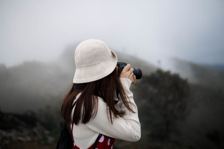 Rear view of woman wearing hat standing on mountain