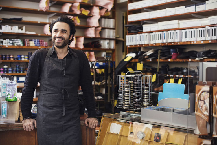 Smiling man standing in shoe repair store