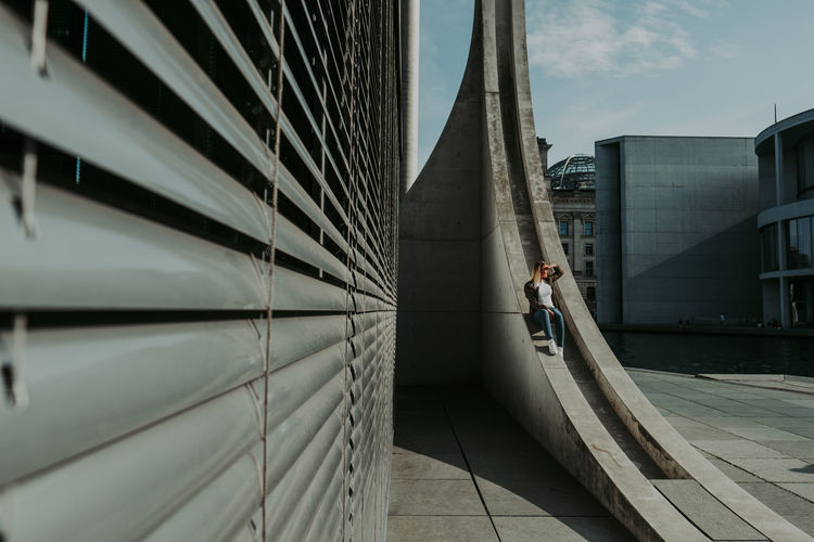 Man walking on bridge against buildings in city