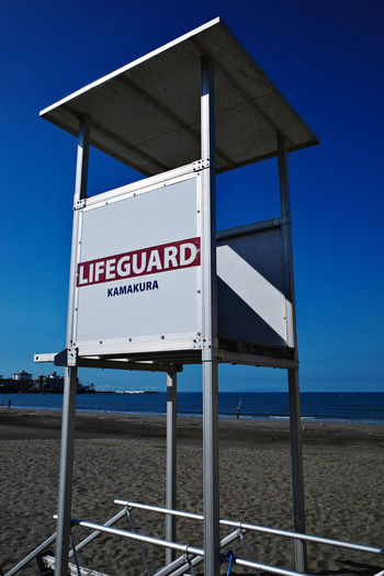 Information sign on beach against blue sky