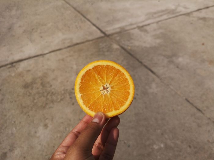 High angle view of hand holding orange