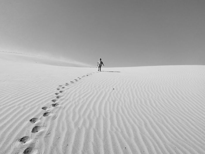 Toddler walking on desert against sky during sunny day