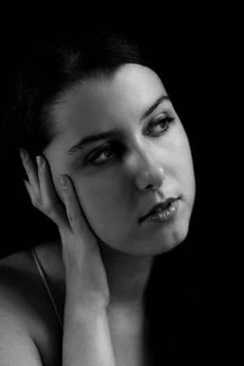 Close-up of young woman over black background