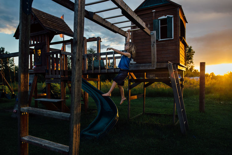 Young boy on play center at sunset