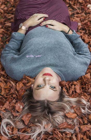 High angle view of woman lying down on autumn leaves
