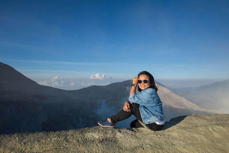 Side view full length of woman sitting on mountain