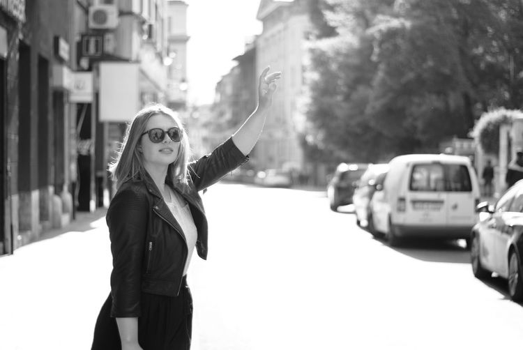 Woman hailing taxi on street in city