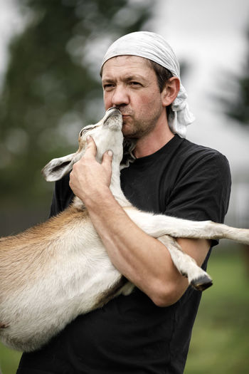 Local agriculture, farmer's day 12 october. a man with a goat in his arms,  natural products.