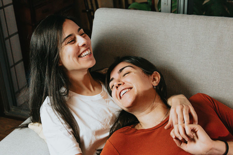 Lesbian couple embracing while lying on sofa at home