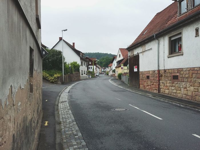 Empty road leading towards buildings