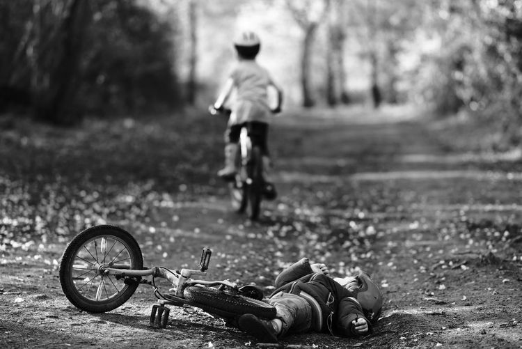 Boy falling off bicycle on dirt road