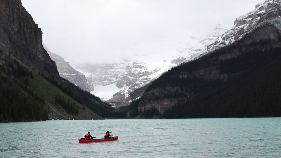 People on boat in lake against sky