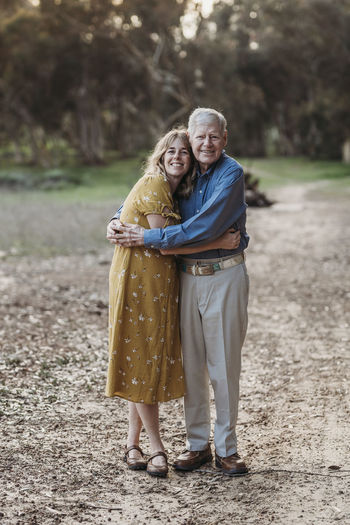 Portrait of adult woman and senior father embracing at park