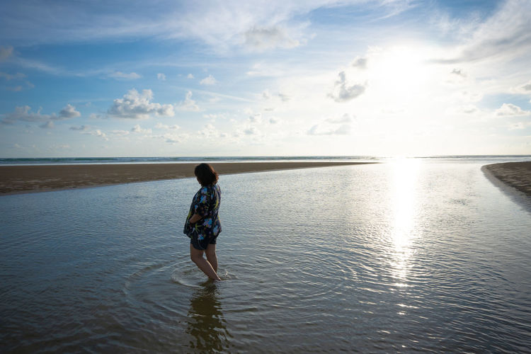 Rear view of girl on beach against sky