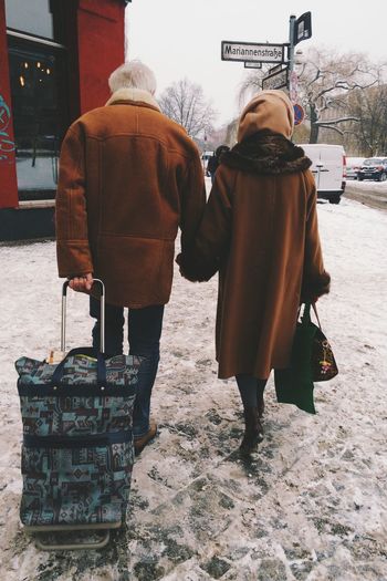 Two people walking with luggage in winter