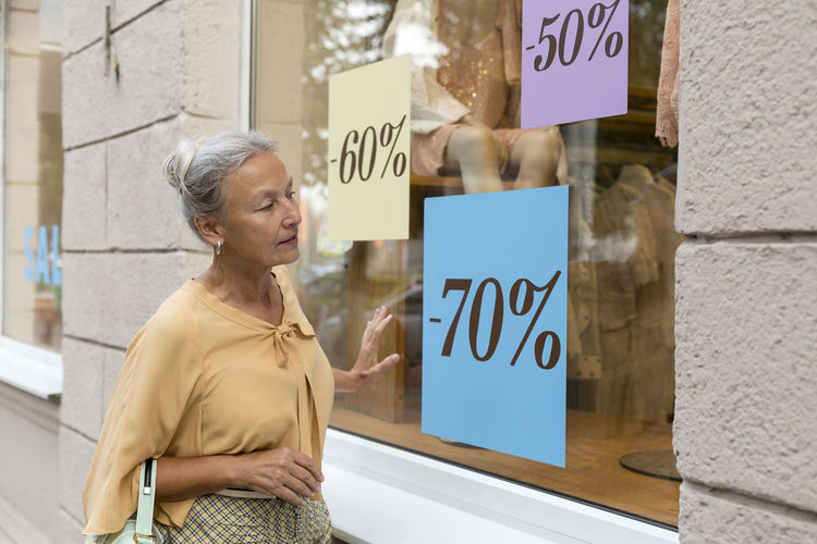 Senior woman looking in shop window of a boutique